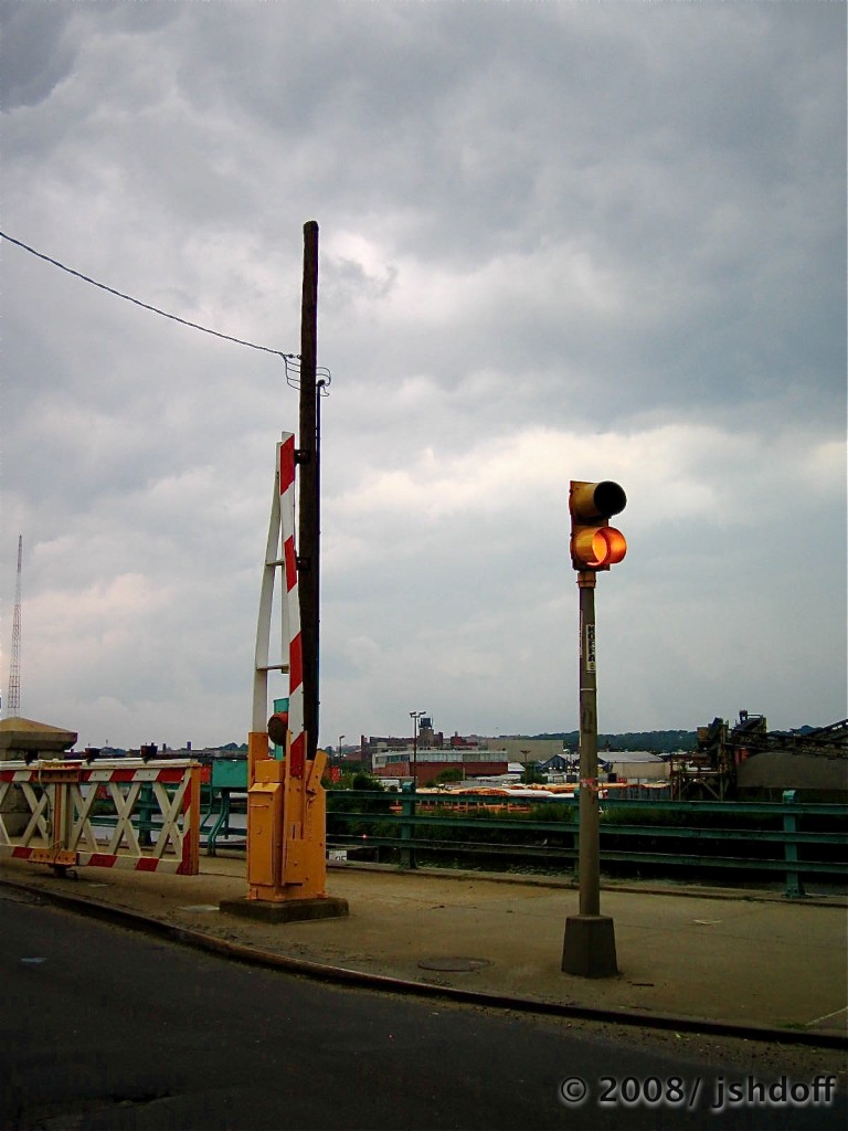 Somewhere, lost in the back-roads of Queenz. A drawbridge. A stoplight that flashes only red, or yel